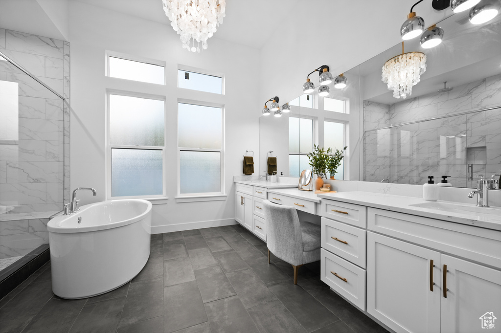 Full bathroom featuring a chandelier, a soaking tub, vanity, a marble finish shower, and baseboards
