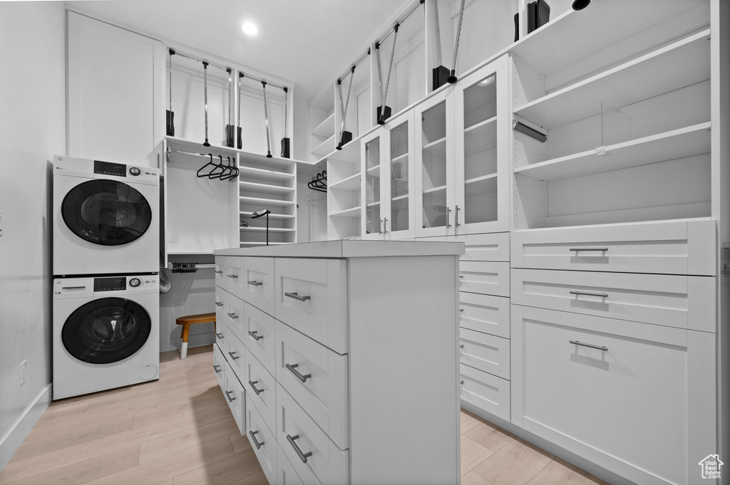 Walk in closet featuring stacked washing machine and dryer and light wood-style floors