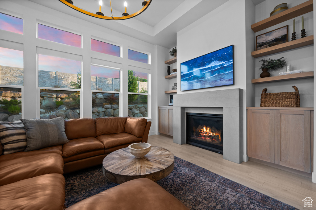 Living area with light wood finished floors, a glass covered fireplace, and built in shelves