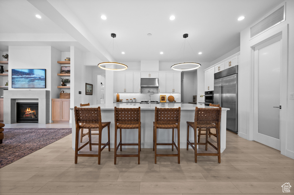 Kitchen with appliances with stainless steel finishes, light countertops, white cabinetry, light wood-type flooring, and recessed lighting