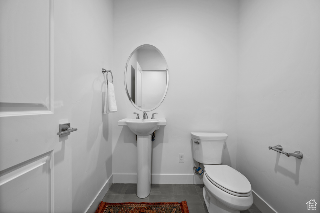 Half bath featuring toilet, baseboards, and tile patterned floors