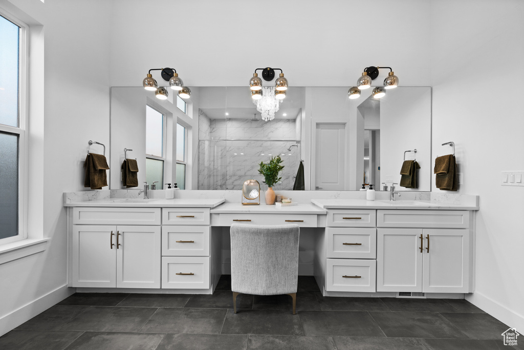 Bathroom with two vanities, a marble finish shower, baseboards, and a chandelier