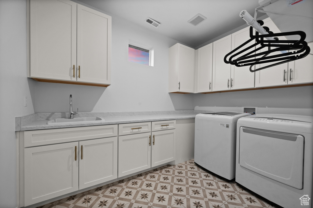Laundry area with washing machine and clothes dryer, cabinet space, and light flooring