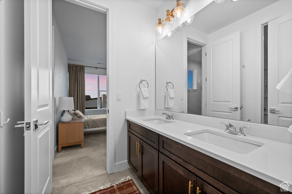 Bathroom featuring double vanity, connected bathroom, and baseboards
