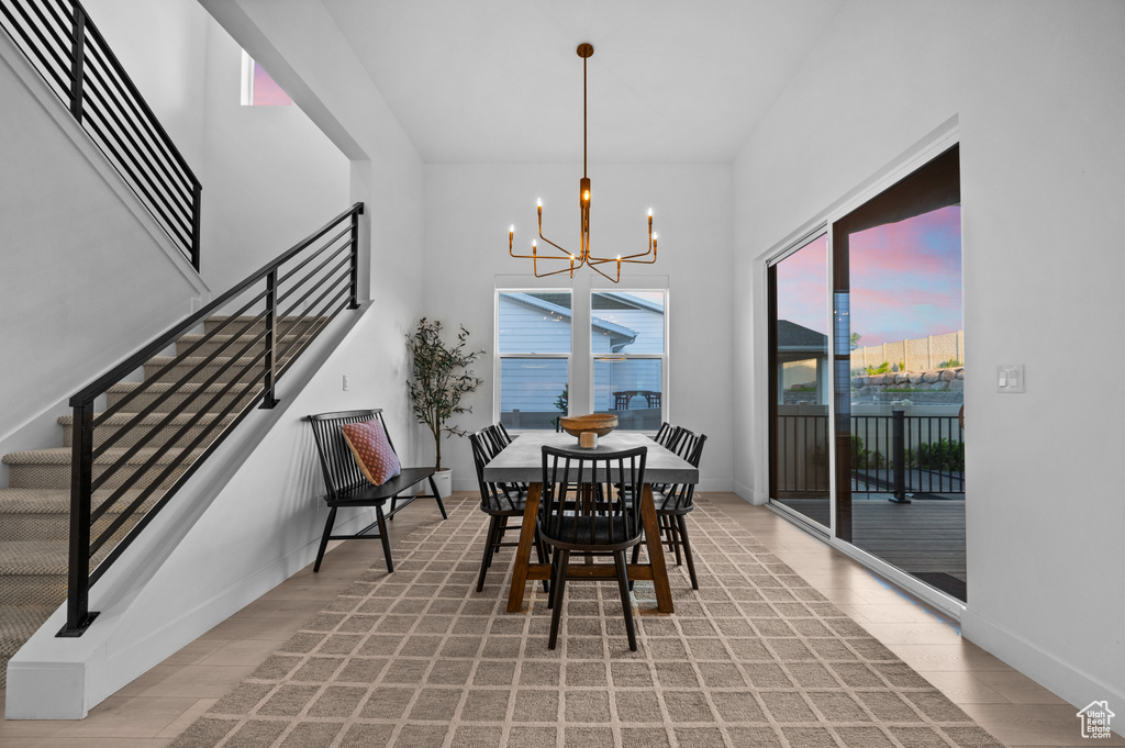 Dining room featuring a chandelier, stairway, a towering ceiling, baseboards, and light wood-type flooring