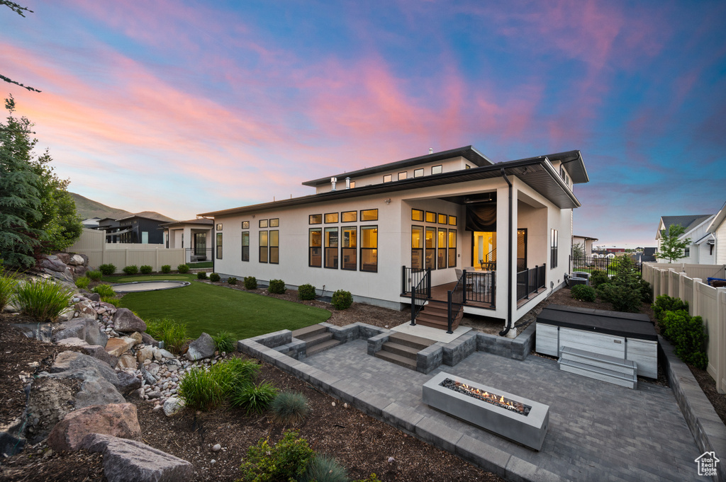 Rear view of house featuring a patio, a fire pit, and stucco siding