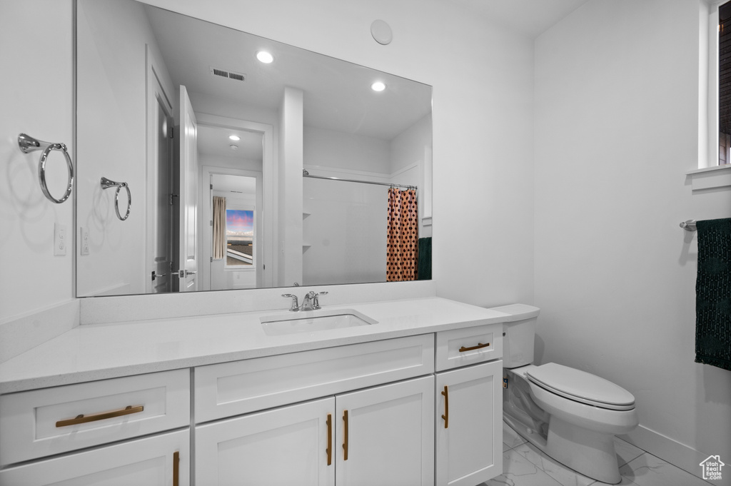 Full bathroom with marble finish floors, vanity, toilet, recessed lighting, and baseboards