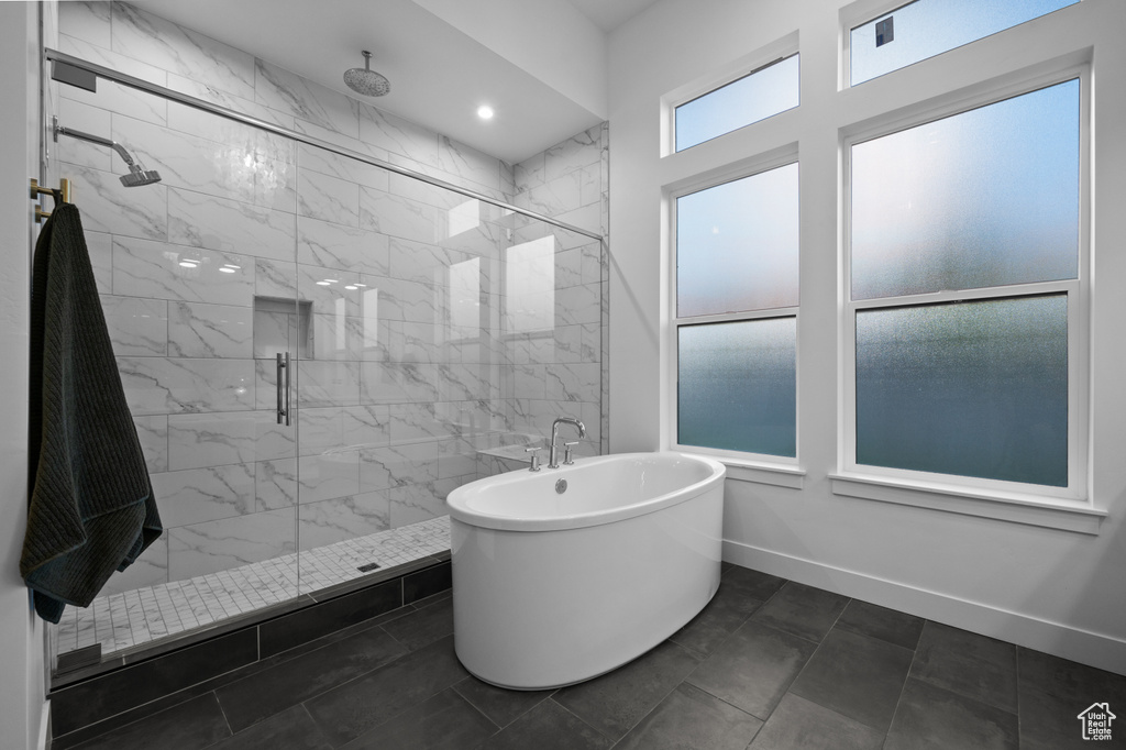 Full bathroom featuring a soaking tub, a marble finish shower, and baseboards