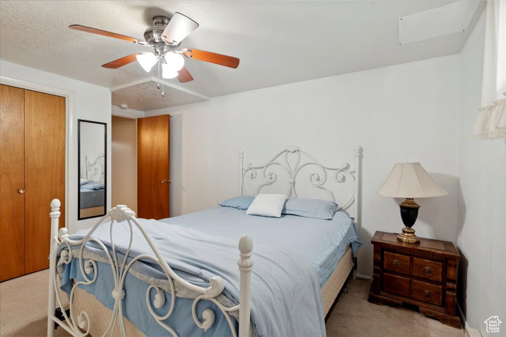 Carpeted bedroom featuring ceiling fan and a closet