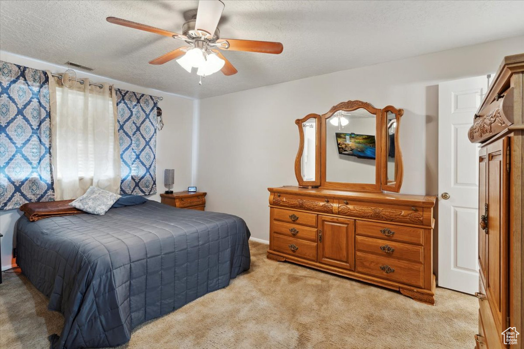 Bedroom featuring light carpet, a ceiling fan, and a textured ceiling