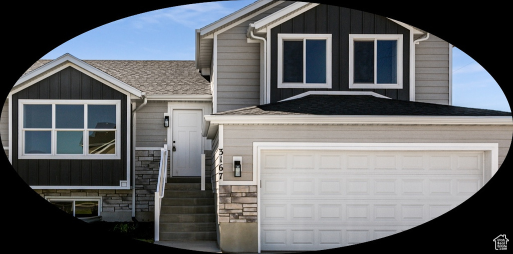 View of front facade featuring a shingled roof, a garage, and stone siding