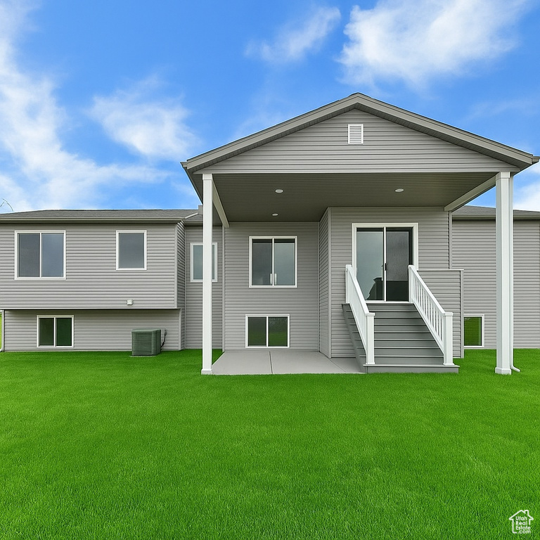 Back of house with a patio, a lawn, and central AC