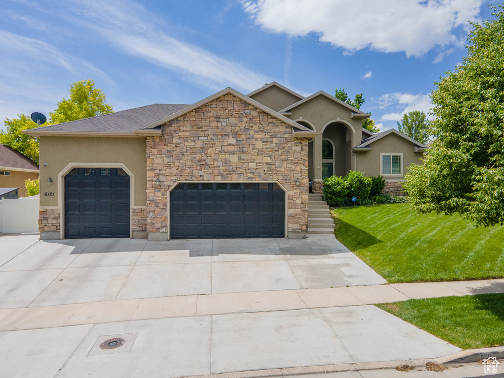 View of front of property featuring stucco siding, a front yard, concrete driveway, and a garage