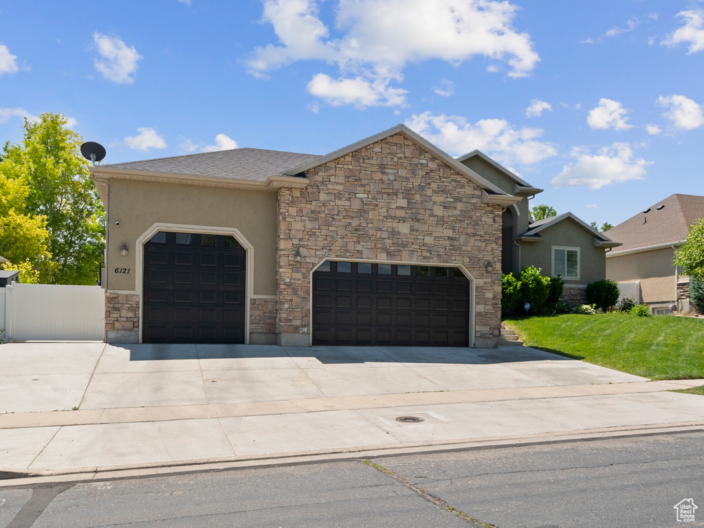 View of front of property featuring concrete driveway, stone siding, an attached garage, and stucco siding