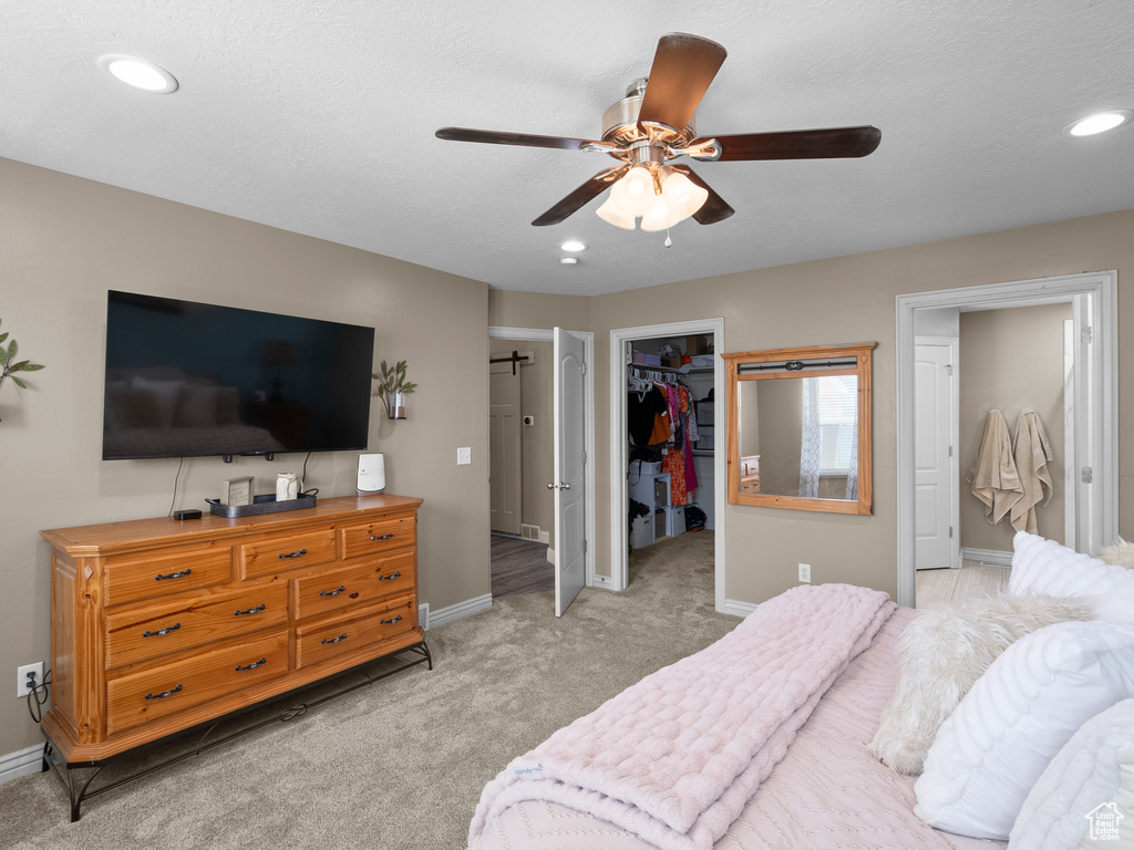 Bedroom featuring baseboards, a spacious closet, light colored carpet, recessed lighting, and a ceiling fan