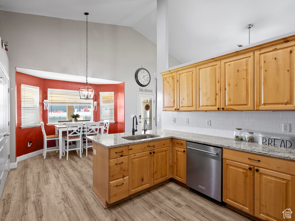 Kitchen with dishwasher, a sink, backsplash, a peninsula, and high vaulted ceiling