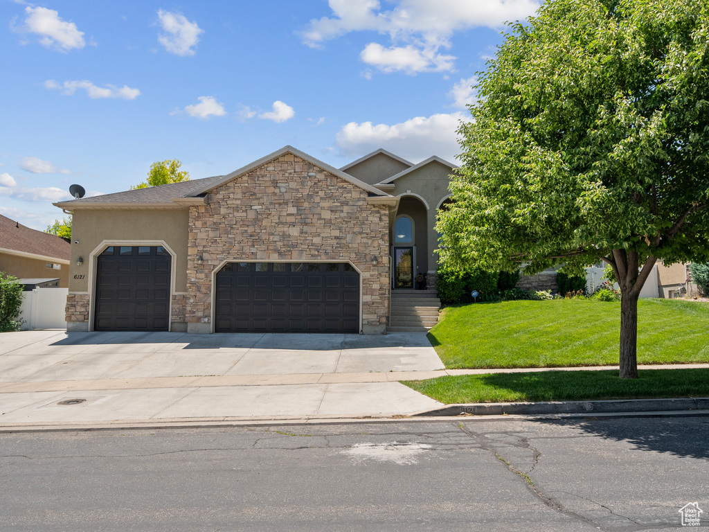 View of front of property featuring stucco siding, a front lawn, concrete driveway, and a garage
