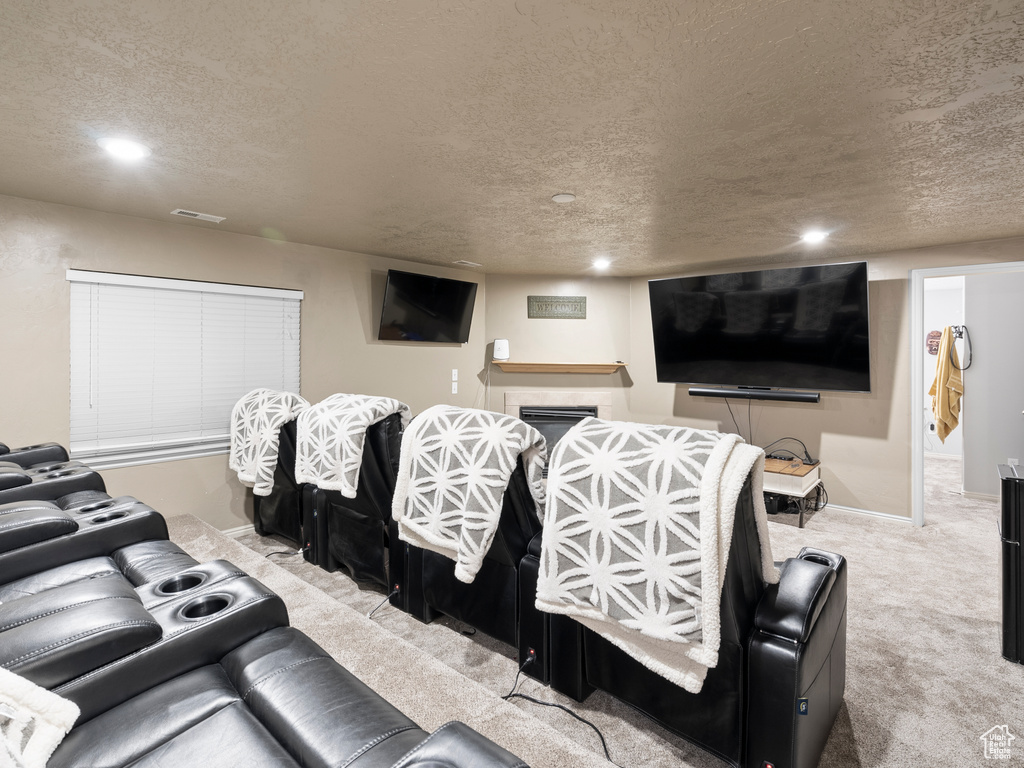 Cinema room featuring a textured ceiling, carpet, recessed lighting, baseboards, and a fireplace