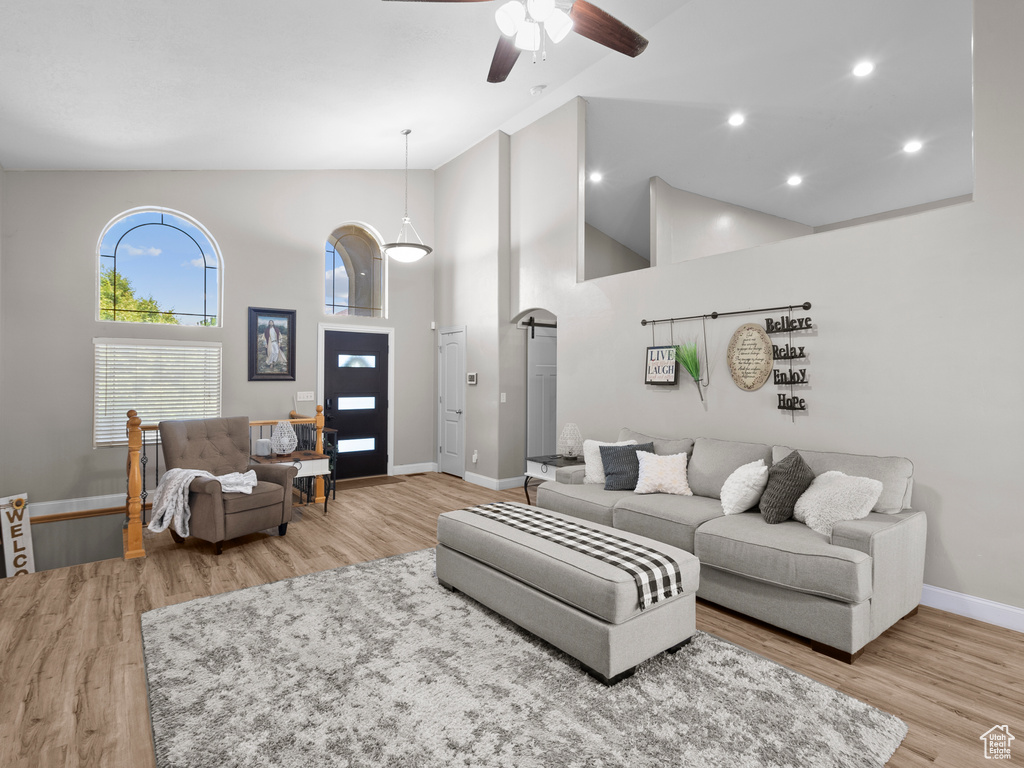 Living area featuring high vaulted ceiling, baseboards, ceiling fan, light wood-type flooring, and recessed lighting