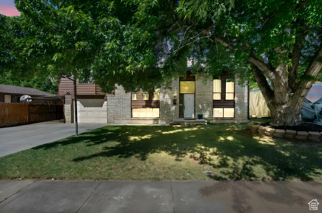 Obstructed view of property with concrete driveway, brick siding, and an attached garage