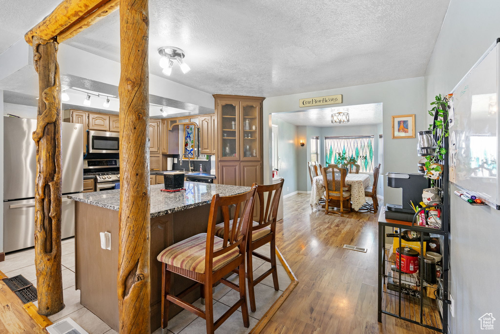 Dining area with light wood finished floors, a textured ceiling, and baseboards