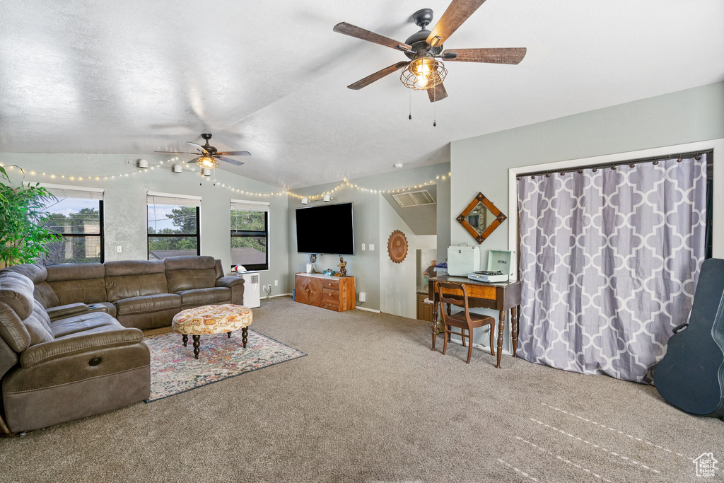 Carpeted living room with ceiling fan and vaulted ceiling