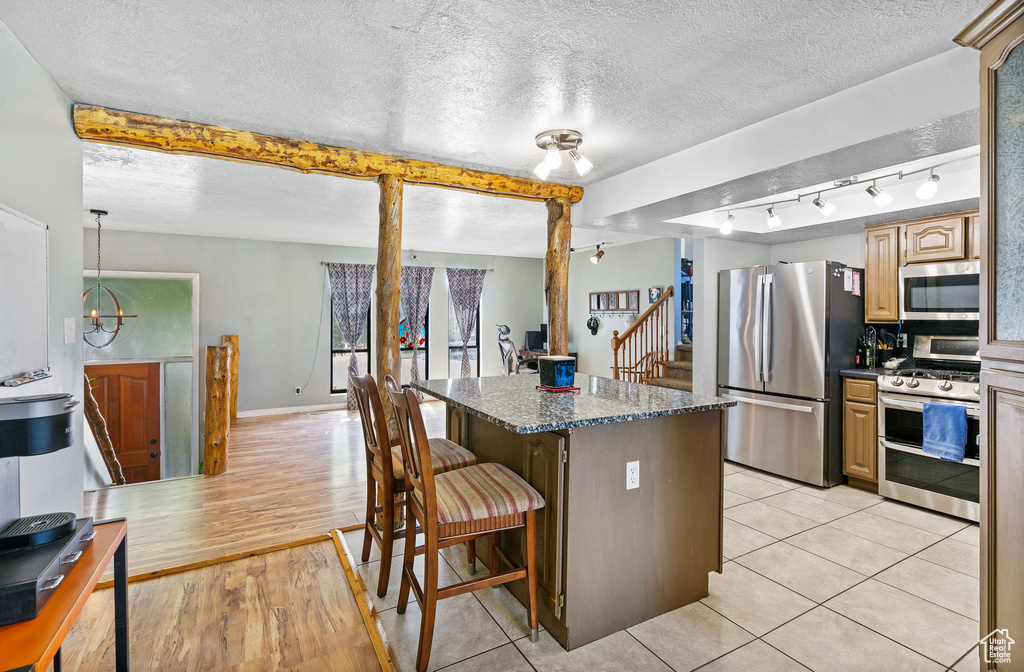 Kitchen featuring appliances with stainless steel finishes, a breakfast bar, a center island, a textured ceiling, and rail lighting
