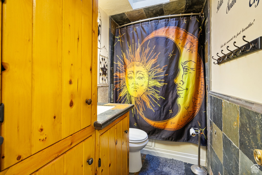 Bathroom featuring toilet, a shower with shower curtain, and vanity