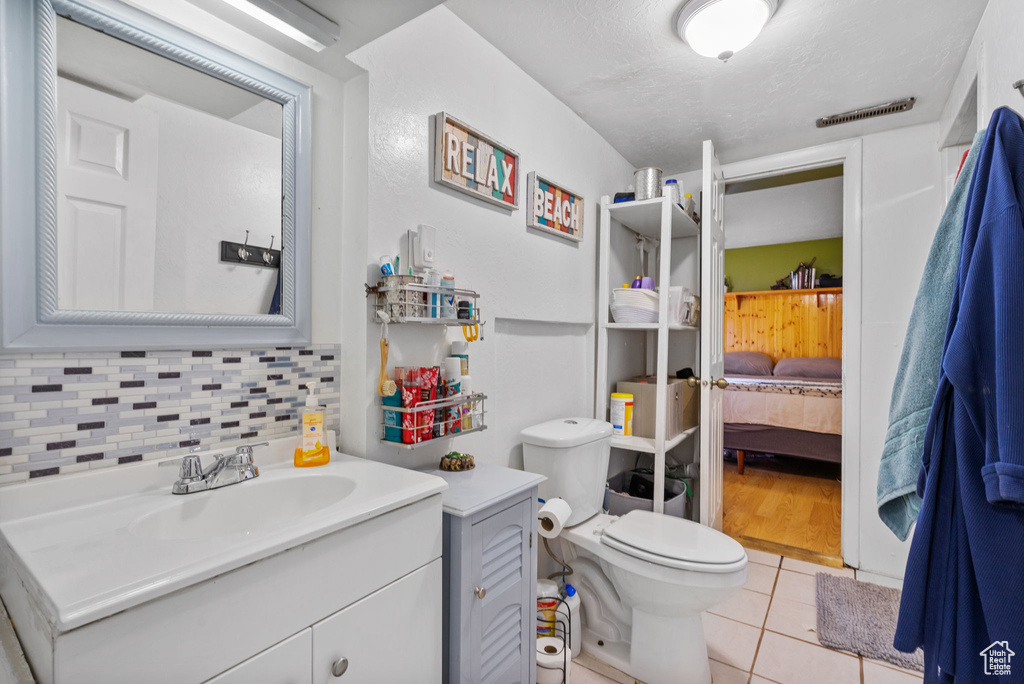 Bathroom with vanity, tile patterned floors, connected bathroom, decorative backsplash, and toilet
