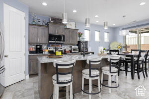 Kitchen with stainless steel microwave, light countertops, recessed lighting, a kitchen bar, and an island with sink