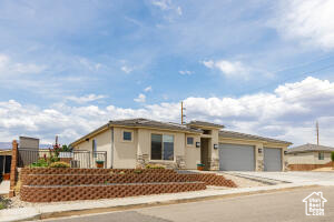 View of front facade with an attached garage, driveway, and stucco siding