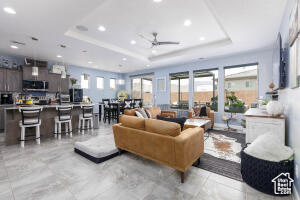 Living area featuring a raised ceiling, recessed lighting, and ceiling fan