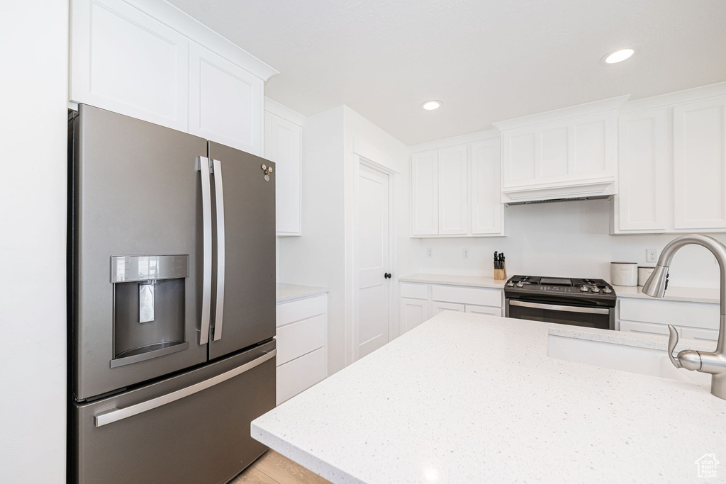 Kitchen featuring appliances with stainless steel finishes, a sink, white cabinets, recessed lighting, and light stone countertops
