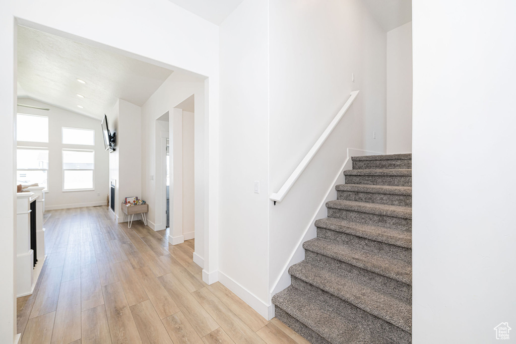 Staircase with vaulted ceiling, wood finished floors, and baseboards