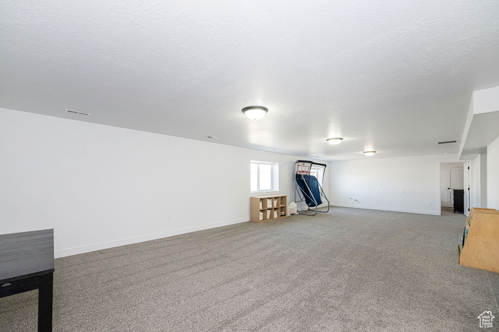 Basement with light colored carpet, baseboards, and a textured ceiling
