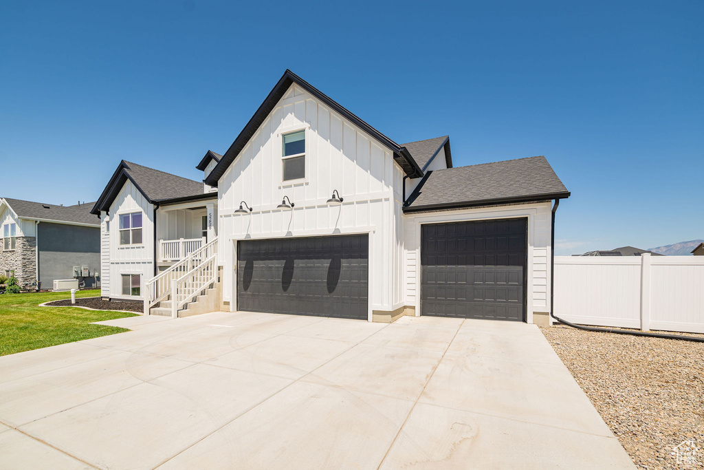 Modern farmhouse style home featuring board and batten siding, driveway, a garage, and a shingled roof
