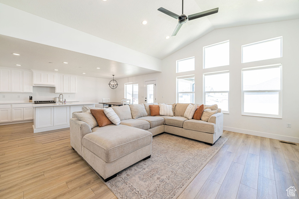 Living area featuring light wood-style flooring, recessed lighting, a ceiling fan, high vaulted ceiling, and baseboards
