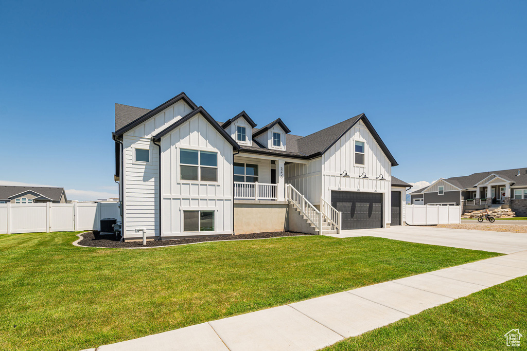 Modern farmhouse with board and batten siding, an attached garage, driveway, and a porch