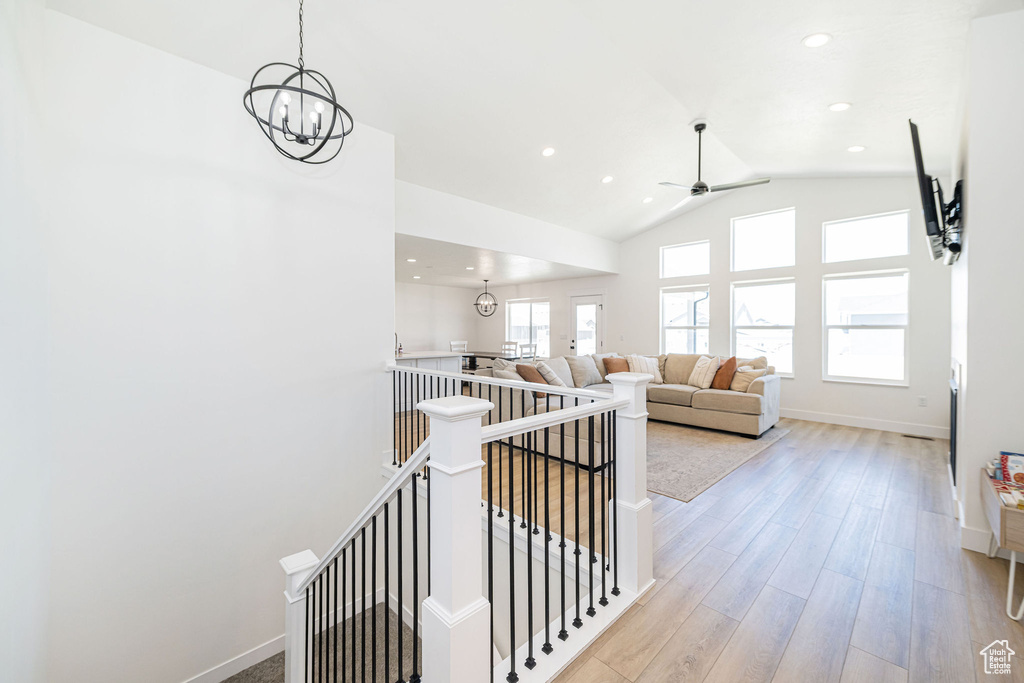 Hall with an upstairs landing, baseboards, wood finished floors, lofted ceiling, and recessed lighting