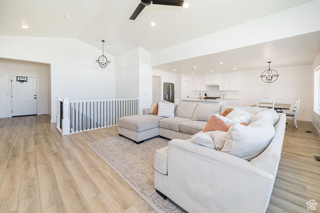 Living area with vaulted ceiling, light wood-style floors, a chandelier, ceiling fan, and recessed lighting