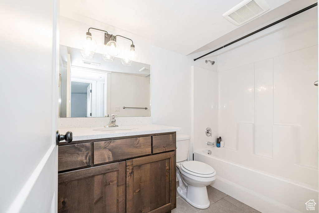Full bath featuring tile patterned flooring, toilet, vanity, and washtub / shower combination