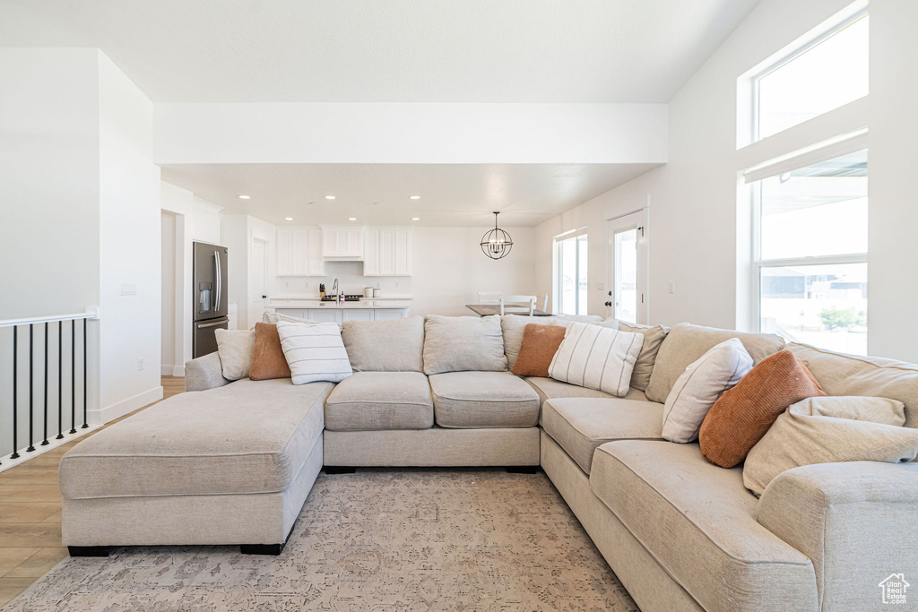 Living area with light wood finished floors, a chandelier, and recessed lighting