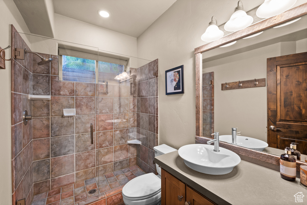 Bathroom featuring vanity, a tile shower, and toilet