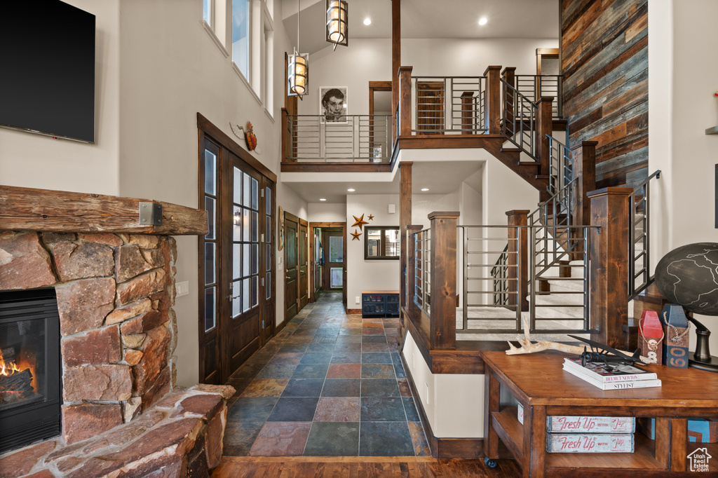 Entrance foyer featuring stairway, a high ceiling, stone finish flooring, french doors, and a stone fireplace