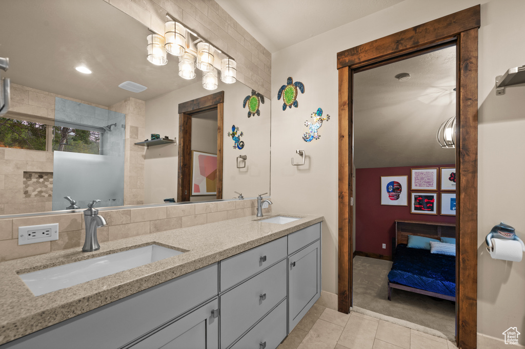 Ensuite bathroom with double vanity, tile patterned floors, and a shower