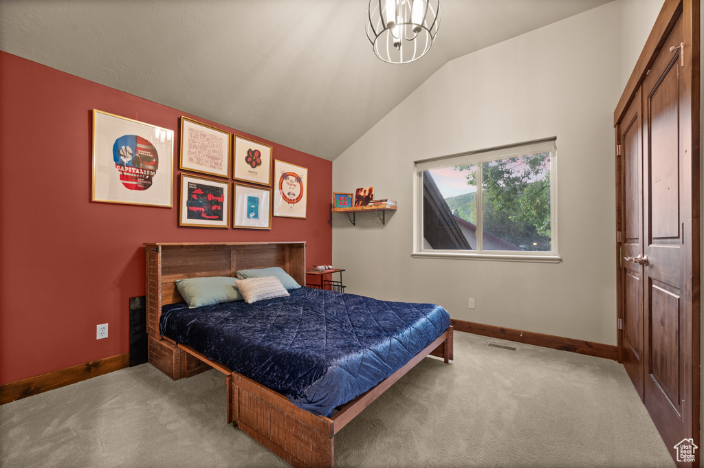 Carpeted bedroom featuring baseboards, vaulted ceiling, and a chandelier