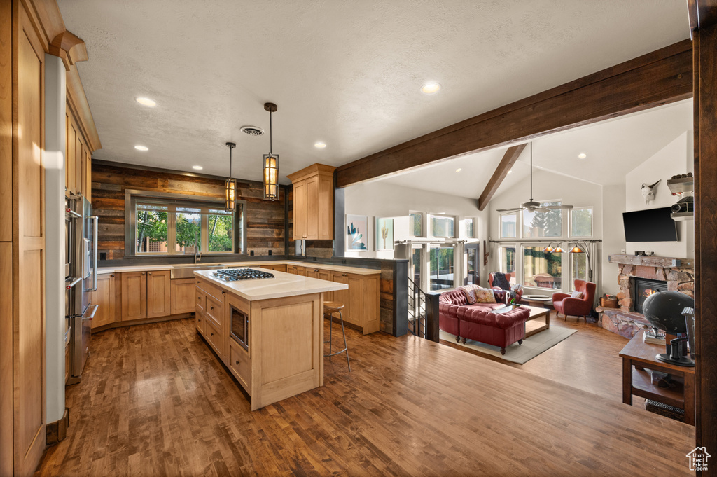 Kitchen featuring open floor plan, a fireplace, a sink, dark wood-style flooring, and ceiling fan