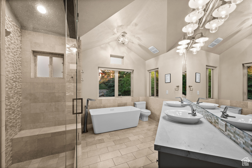 Full bathroom with tile walls, double vanity, a freestanding bath, a shower stall, and tile patterned floors