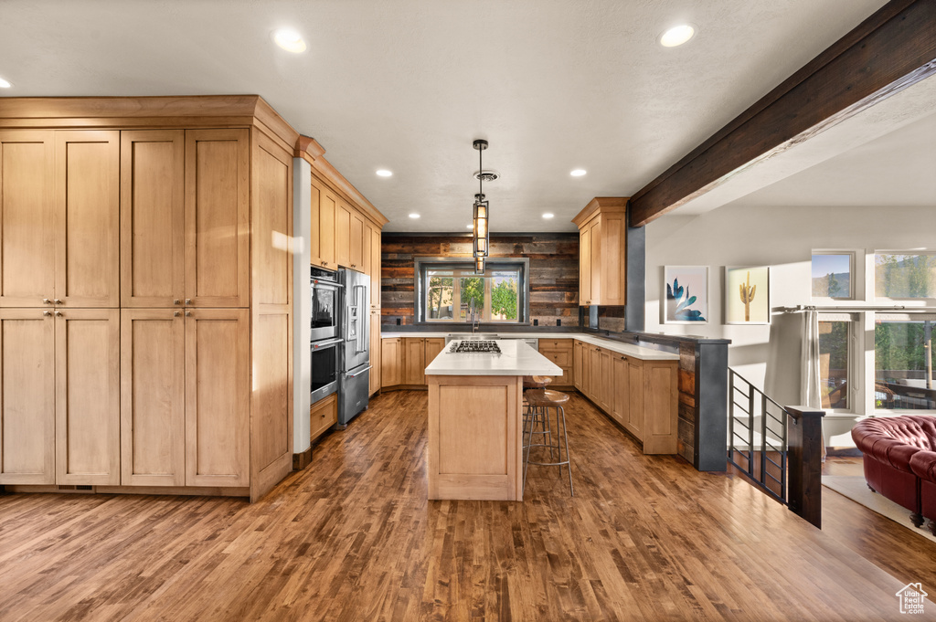 Kitchen with recessed lighting, light countertops, a breakfast bar area, a peninsula, and wood finished floors