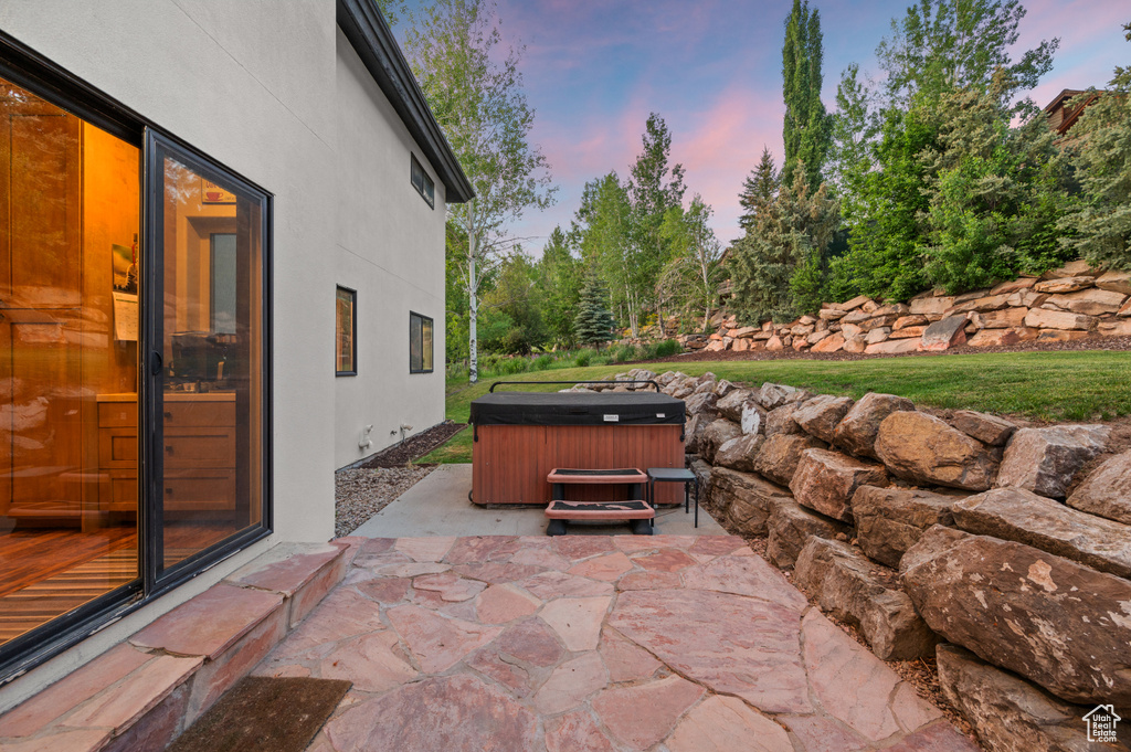 Patio terrace at dusk featuring a hot tub and a patio area